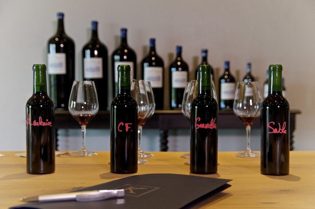 Table de dégustation avec échantillons de cépages et verres de vin, illustrant un atelier œnologique haut de gamme d’assemblage.