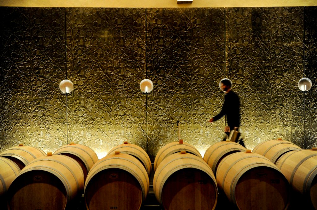 Professionnel travaillant dans un chai à barriques, illustrant le soin apporté à l’élevage des vins au cœur du savoir-faire viticole bordelais.