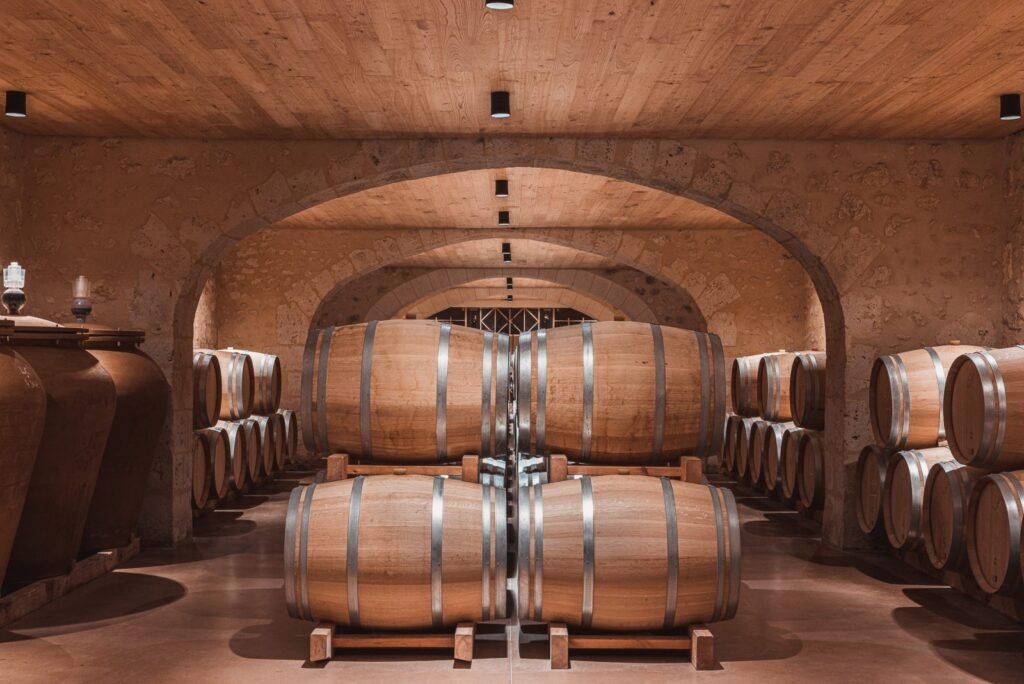 Cave voûtée de Saint-Émilion avec rangées de barriques en chêne, idéale pour une visite œnologique haut de gamme à Bordeaux.
