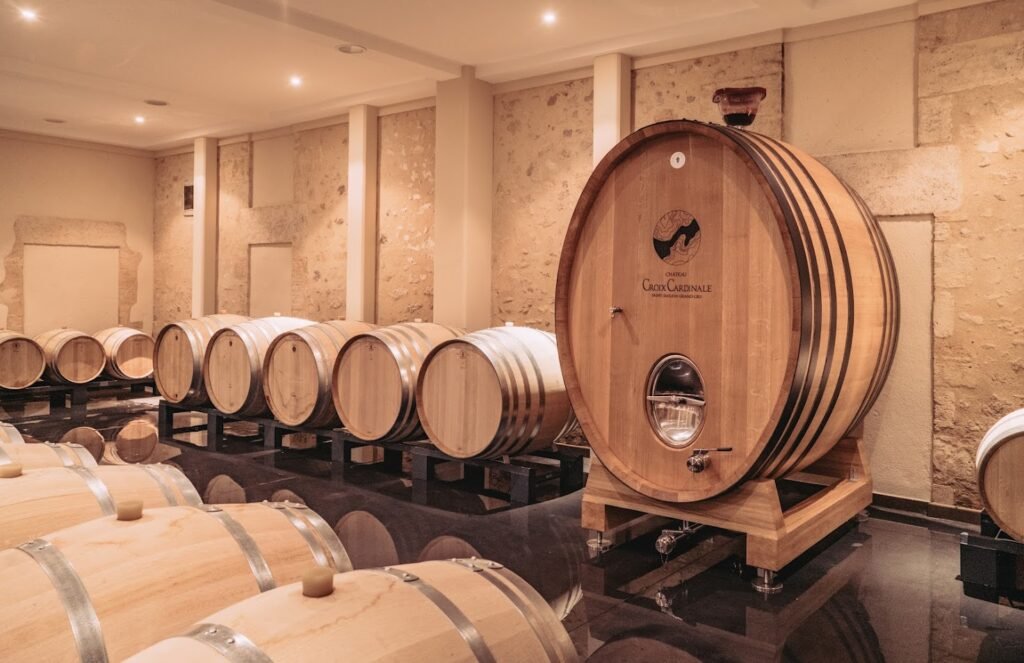 Chai de vinification à Saint-Émilion avec barriques en chêne et grand foudre du Château Croix Cardinale