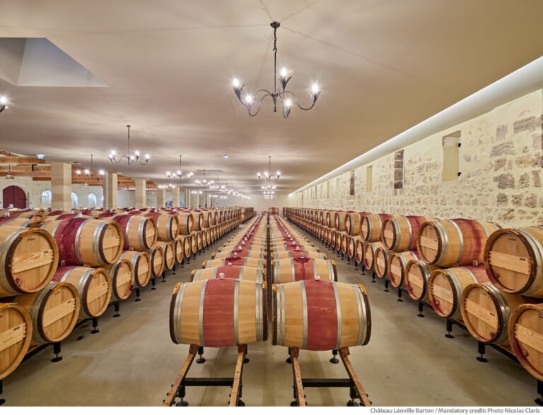 Chai traditionnel du Château Léoville Barton dans le Médoc, avec rangées de barriques en élevage, au cœur d’une visite œnologique à Bordeaux.