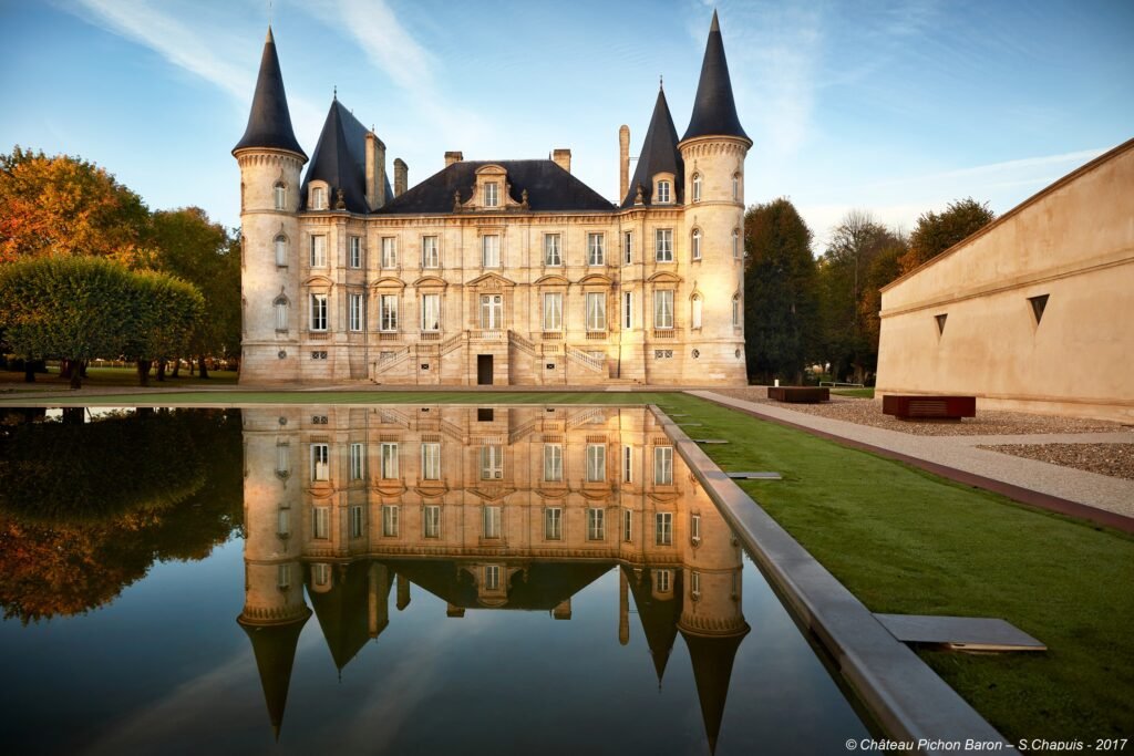 Façade majestueuse d’un château bordelais reflétée dans un bassin, symbole d’élégance et d’histoire au cœur du patrimoine viticole.
