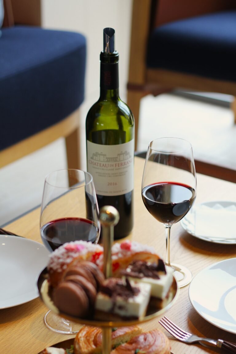 Bouteille de vin du Château de Ferrand accompagnée de deux verres de rouge et d’une sélection de gourmandises, idéale pour une dégustation lors d’un weekend œnologique à Saint-Émilion