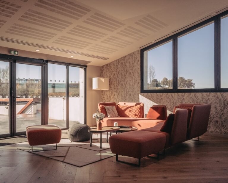 Salon moderne et lumineux avec canapé orange et grandes baies vitrées donnant sur une terrasse