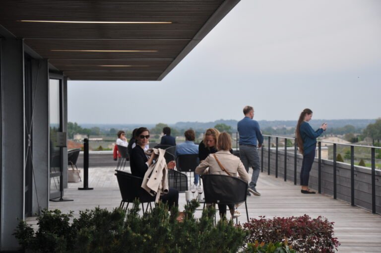 Terrasse panoramique sur les vignobles de Saint-Émilion, où les visiteurs profitent d’une dégustation de vin lors d’une excursion œnologique.