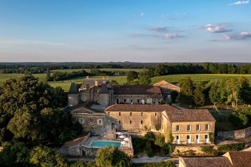 Vue aérienne d’un château au cœur de la campagne bordelaise, cadre idéal pour un séjour œnologique raffiné près de Saint-Émilion.