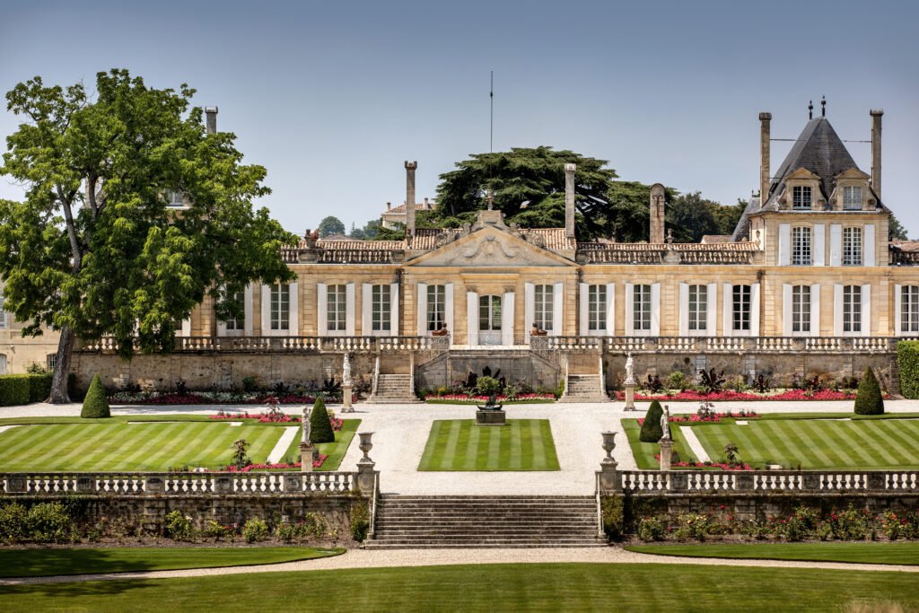 Façade majestueuse d’un château viticole entouré de jardins soignés, idéale pour une visite œnologique près de Bordeaux.