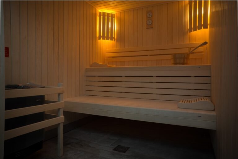 Sauna en bois à la lumière tamisée, avec bancs superposés et ambiance chaleureuse pour un moment de détente.
