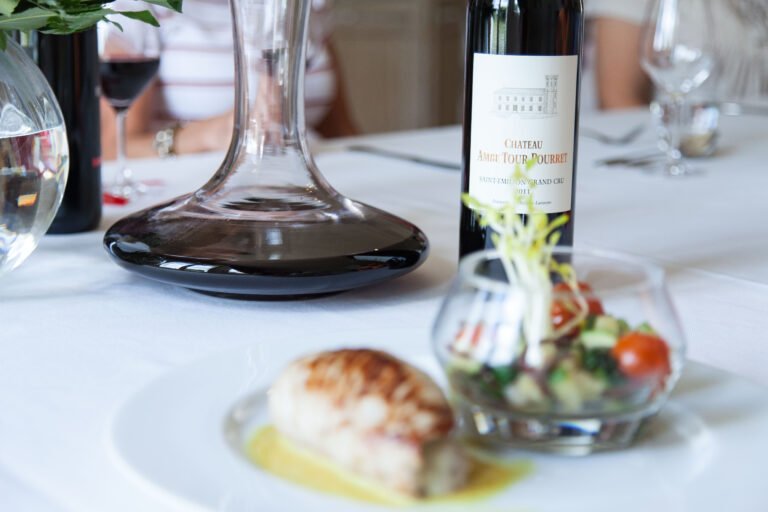 Dégustation gastronomique avec un vin rouge Château Ambe Tour Pourret Saint-Émilion Grand Cru servi en carafe et plats raffinés