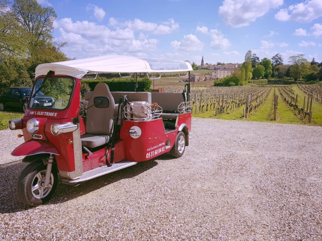 Balade en tuk-tuk à travers les paysages viticoles de Saint-Émilion, une expérience originale et haut de gamme lors d’un séjour œnologique.