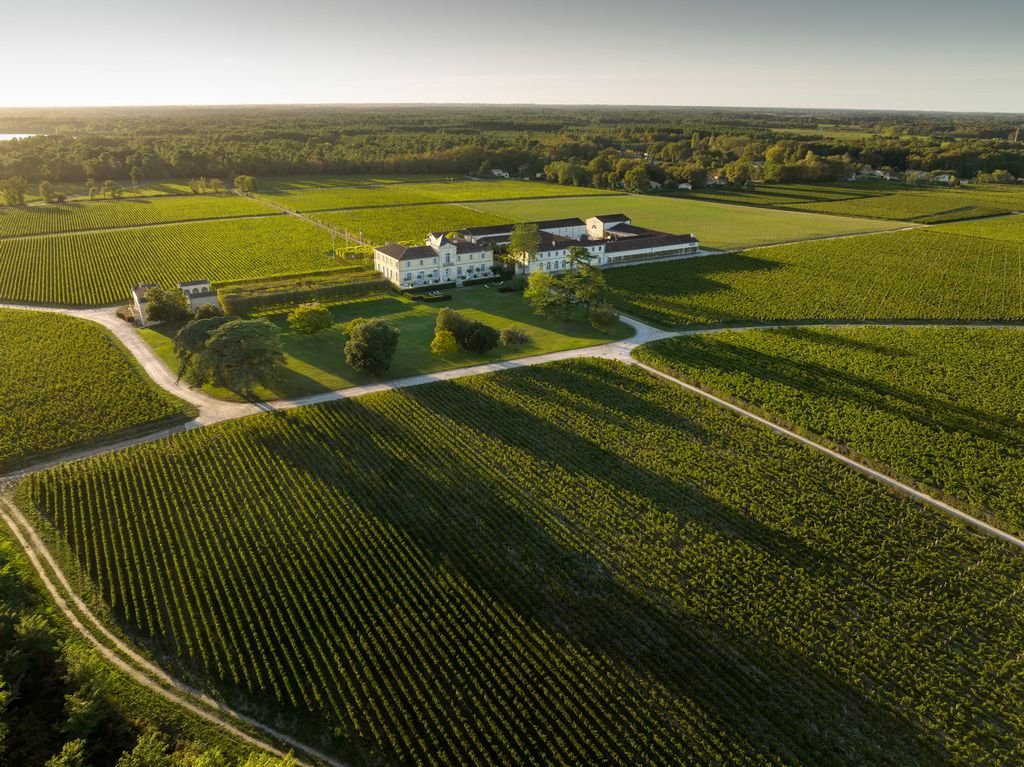 Vue aérienne d’un vaste domaine viticole du Médoc entouré de vignes, cadre d’excursions et de séjours œnologiques dans le vignoble de Bordeaux.